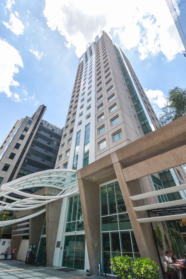 Un immeuble moderne de grande hauteur, doté d’une façade en verre et d’une structure incurvée originale, qui se distingue au premier plan.
