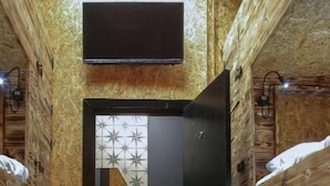 A narrow room with bunk beds, a wooden wall, a small sink, and a mirror. - The Studio (Swansea)