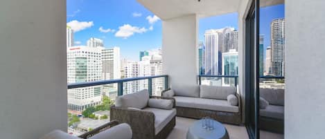 Un balcon avec vue sur la ville, des meubles en osier et une table ronde.