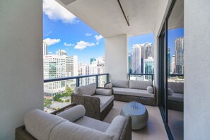 A balcony with a city view, wicker furniture, and a round table.