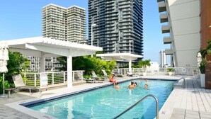 A swimming pool with people in it, surrounded by high-rise buildings. - Stylish 1BR | Free Parking | Walkable Area (Miami)