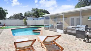 A backyard with a swimming pool, lounge chairs, and a barbecue grill. - Golf and Pool Vacation Home!
 (St. Petersburg)