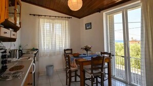 Un coin repas avec une table dressée pour quatre personnes, un plafond en bois et une vue à travers la porte vitrée.
