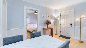 A hotel room with a dining table, chairs, a bedside table with a vase, a lamp, and a door. - Skyline Blue House in Greenwood (Seattle)