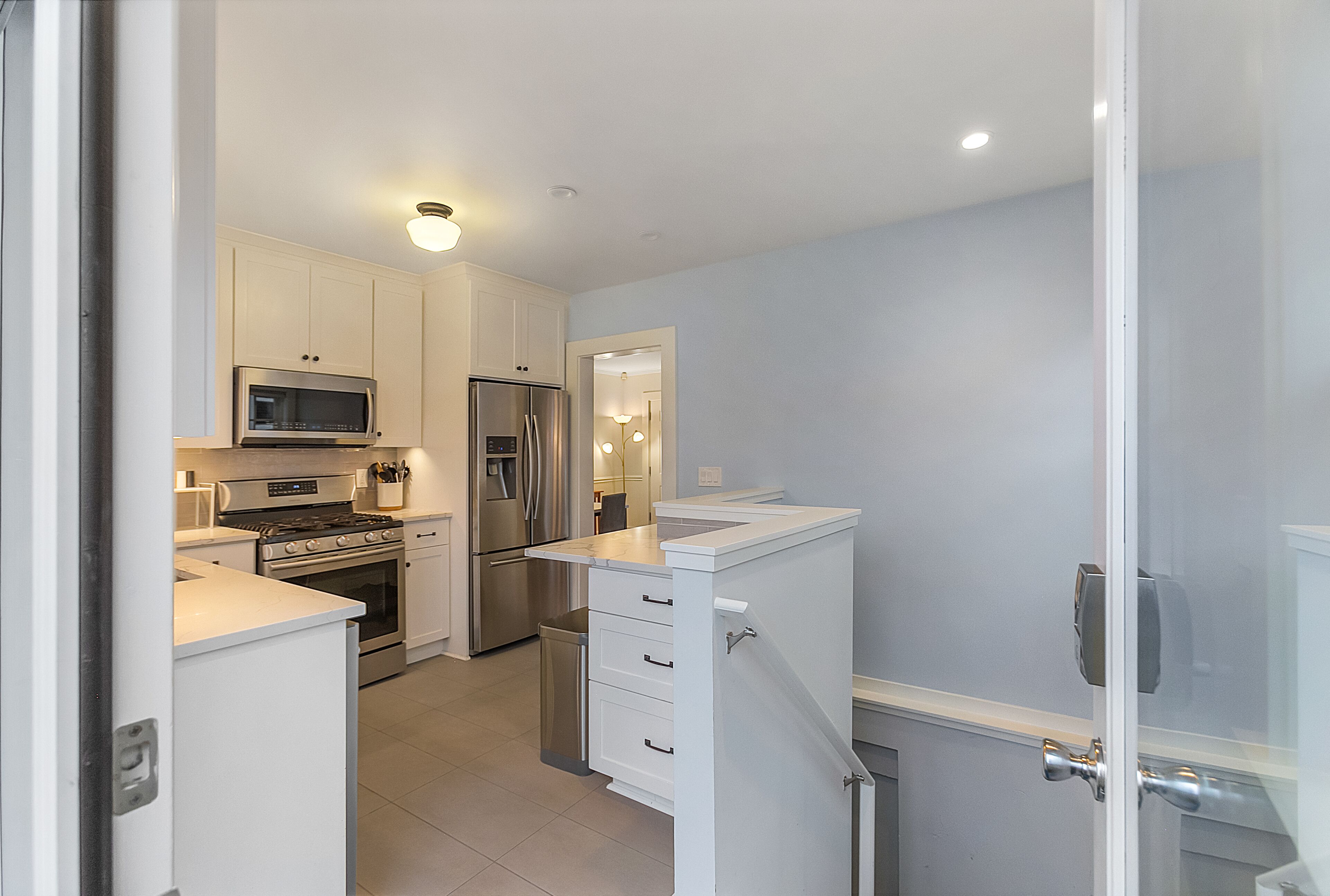 A compact kitchen with white cabinets, stainless steel appliances, and a small countertop.
