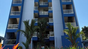 A tall, modern building with multiple balconies and a clear sky. - Oceanfront Condo with stunning pool and oversized balcony. (Jacó)