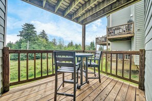 Une terrasse en bois avec une table et des chaises, donnant sur une pelouse et des arbres.
