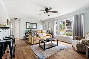 A modern living room with a sofa, coffee table, and a large window with curtains.