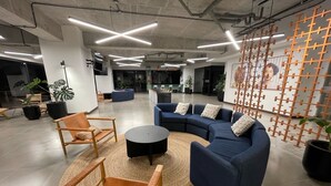 A modern office space with a curved blue sofa, wooden chairs, and a round black table.