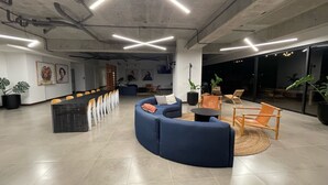 A modern office space with a curved blue sofa, a long table with chairs, and potted plants.