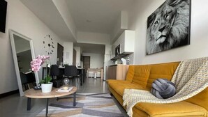 Una sala de estar moderna con un sofá amarillo, una mesa de centro con una flor rosa y una alfombra geométrica.