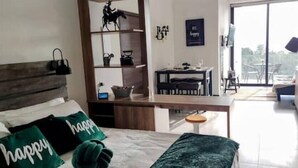Un dormitorio con cama, almohadas, un escritorio y una silla.