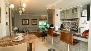 A modern kitchen with a dining area, featuring a wooden table, bar stools, and a chandelier. - PRIME LOK- SP FLAT JARDINS I (São Paulo)