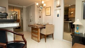 A dining area with a wooden table, chairs, and a chandelier. There is a kitchen visible in the background. - PRIME LOK- SP FLAT JARDINS I (São Paulo)