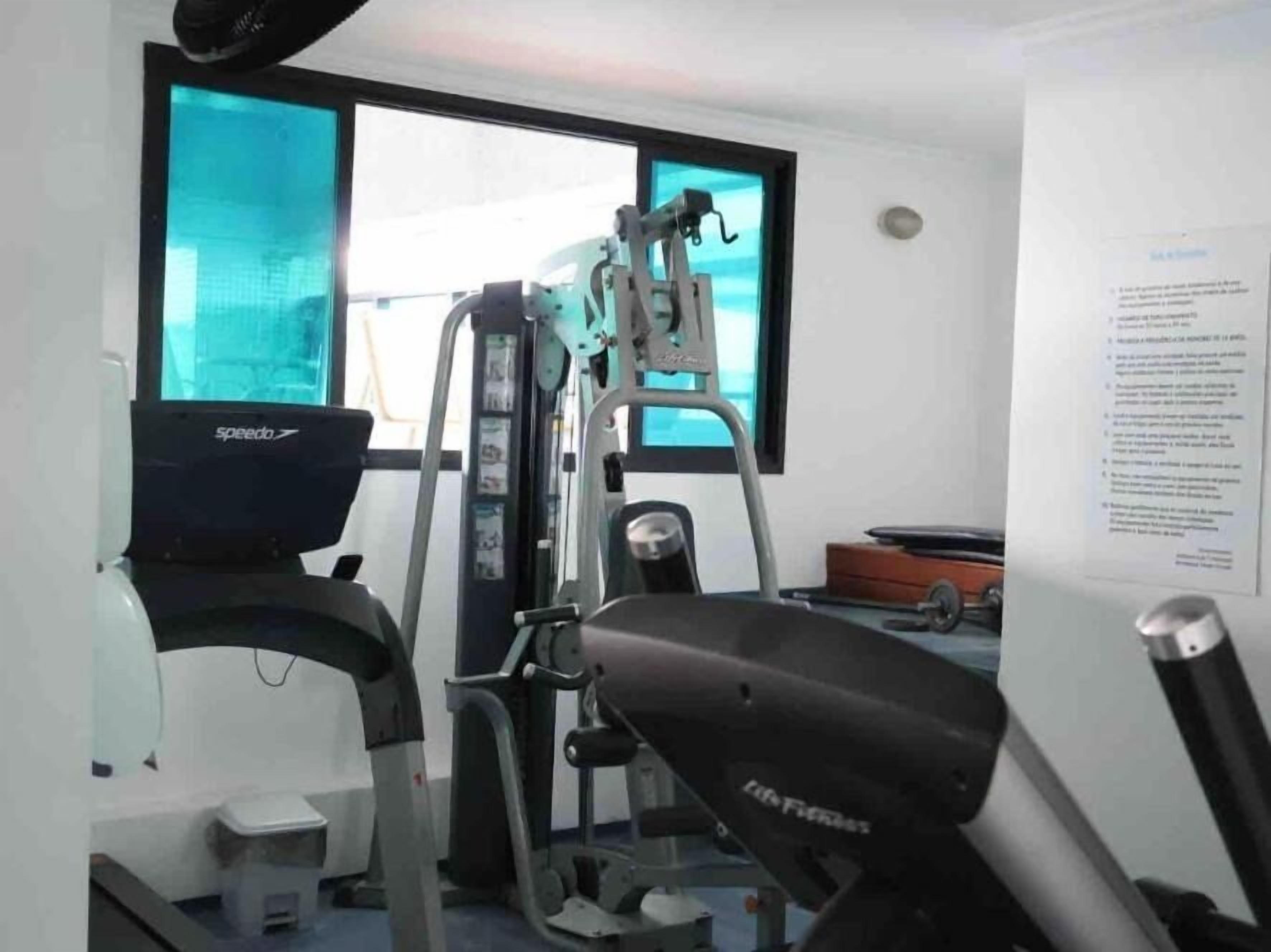 A gym with cardio machines, weight equipment, and a window with a view.