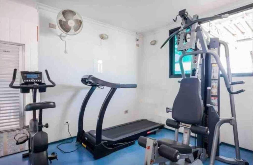 Un gimnasio pequeño con cinta de correr, elíptica y máquina de pesas.