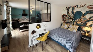 Ein Schlafzimmer mit einem Bett, einem Schreibtisch, einem Stuhl, einem Spiegel und einer Wand mit einem großen Oktopus-Wandbild.