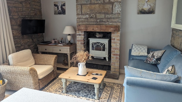 A cozy living room with a stone fireplace, a television, and comfortable seating. - Stunning 1-bed Apartment in Rothbury, Morpeth (Morpeth)