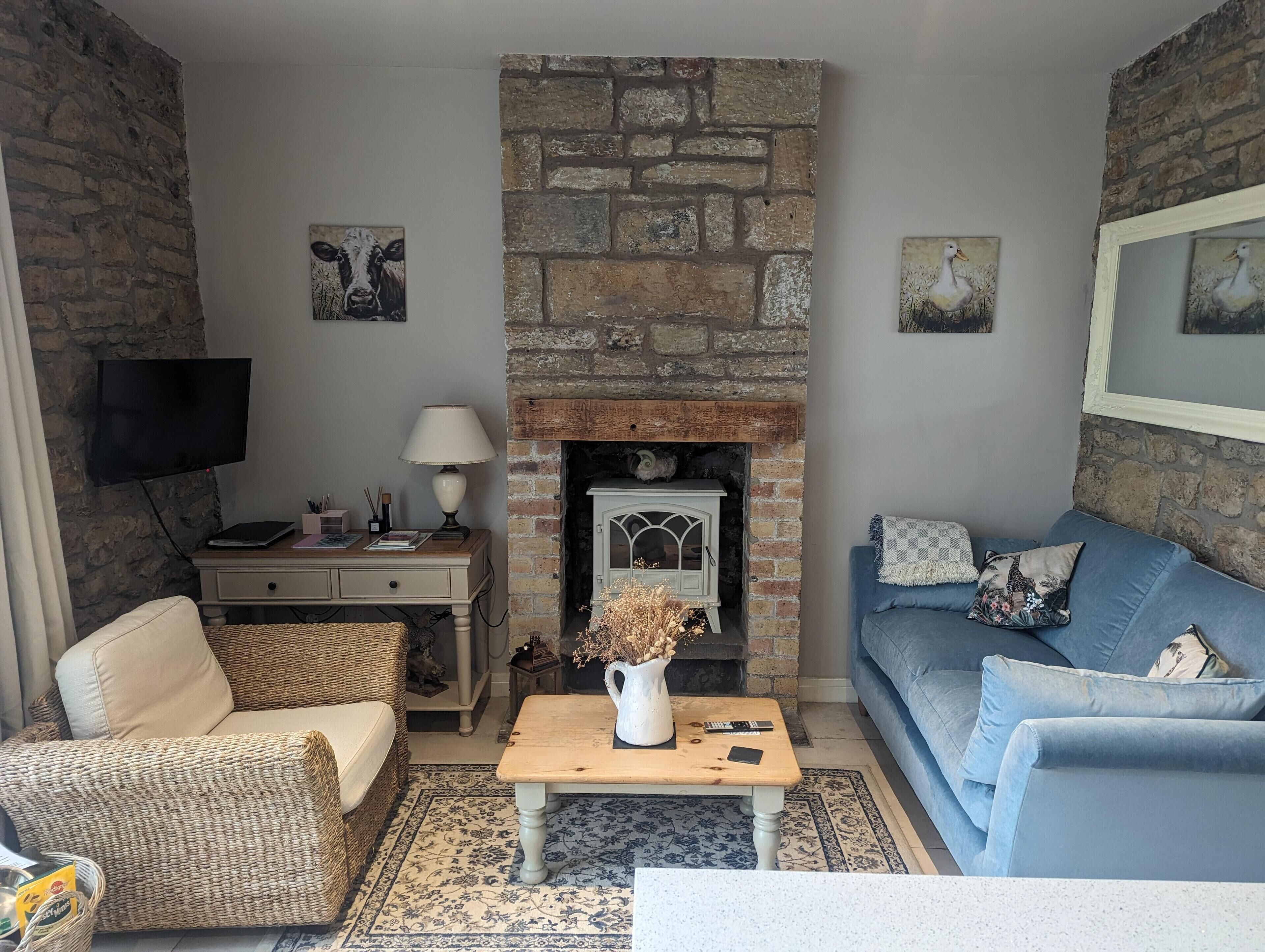 A cozy living room with a stone fireplace, a television, a sofa, and a coffee table.
