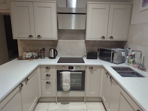A kitchen with a stainless steel range hood, a toaster, a kettle, and a sink with a dish rack. - Stunning 1-bed Apartment in Rothbury, Morpeth (Morpeth)