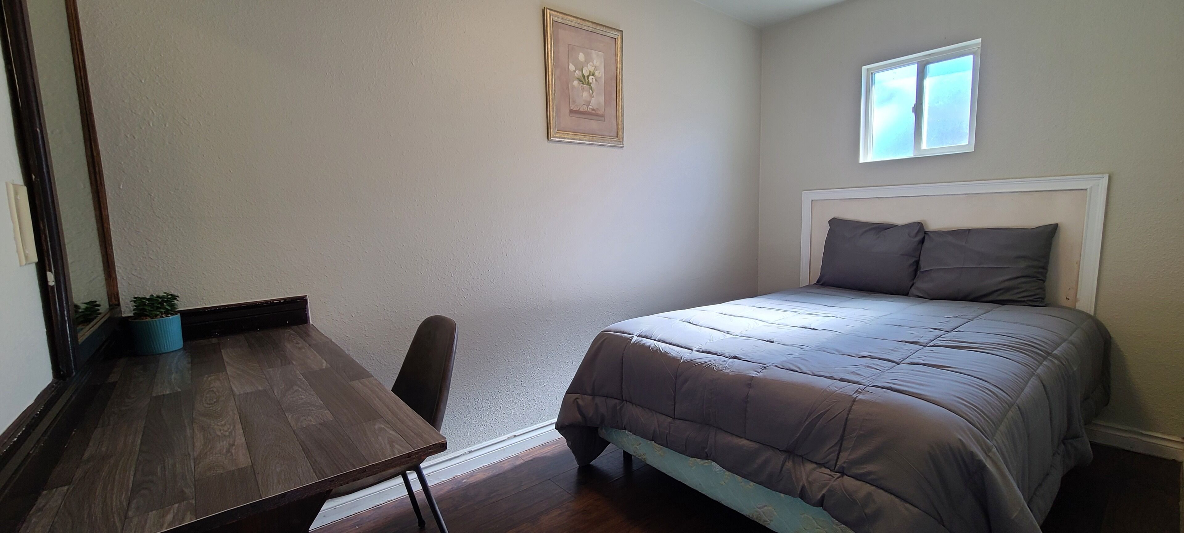 Een slaapkamer met een bed, een bureau en een stoel.