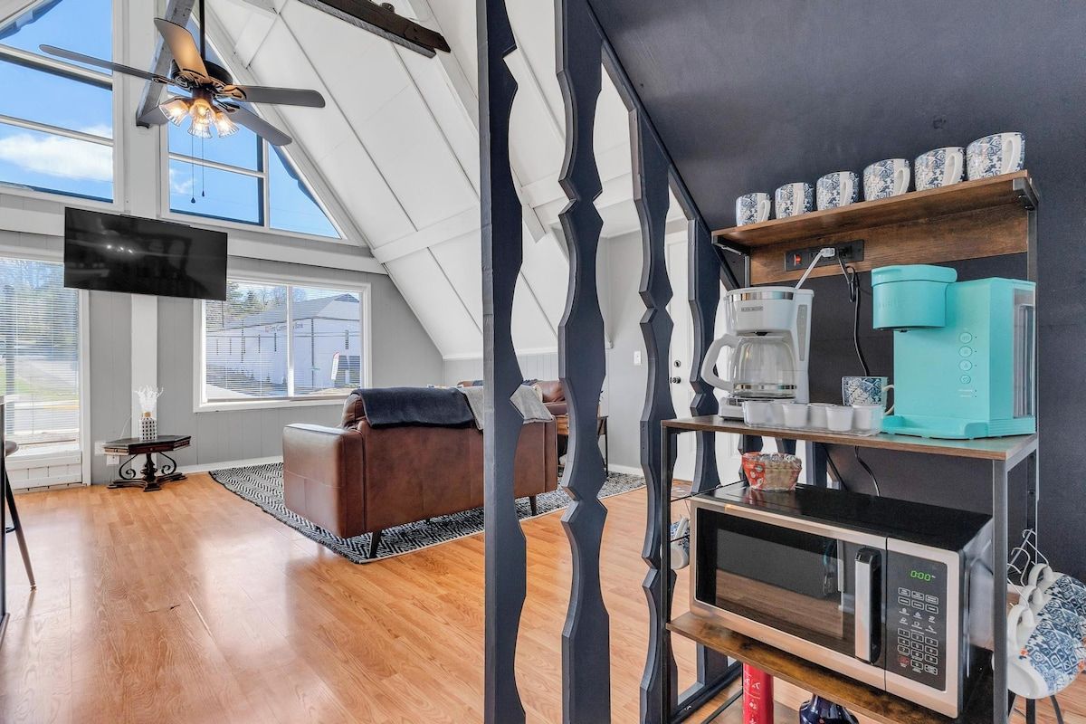 A modern kitchen with a microwave, coffee maker, and decorative items on shelves.