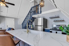 Una cocina con encimera de mármol, electrodomésticos de acero inoxidable y una escalera azul.