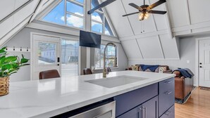 A modern kitchen with a large island, white cabinetry, and a ceiling fan.