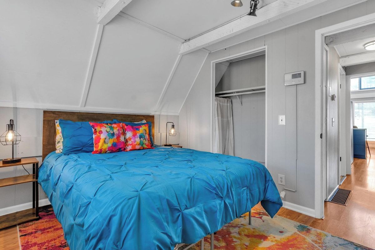 A bedroom with a large bed, a wooden headboard, a colorful rug, and a walk-in closet.