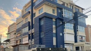A multi-story building with a modern architectural design, featuring a combination of beige and dark blue facades, multiple balconies, and large windows. - Luxury & Secure-Santo Domingo Este-Close & Safe-Weekly Discounts (Santo Domingo Este)