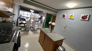 A modern kitchen with a central island, wooden cabinets, and a dining area with chairs and a table. - Luxury & Secure-Santo Domingo Este-Close & Safe-Weekly Discounts (Santo Domingo Este)