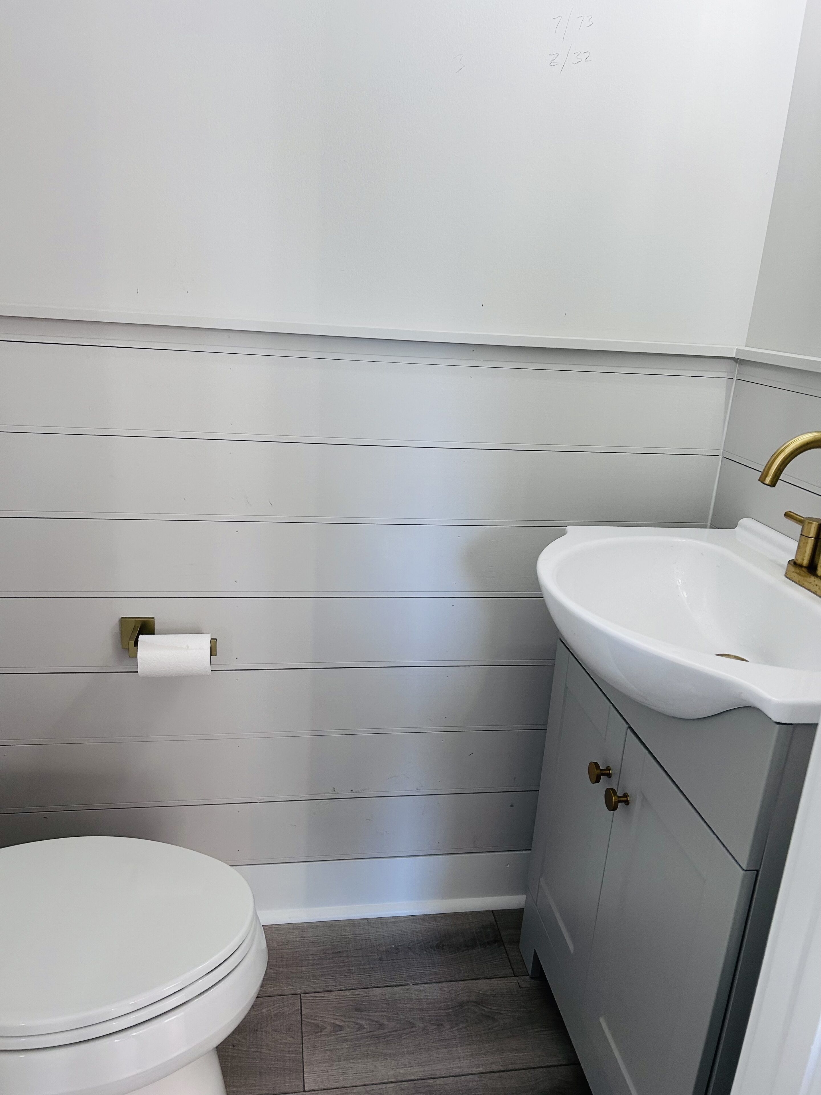 A bathroom with a toilet, a sink, and a toilet paper holder.