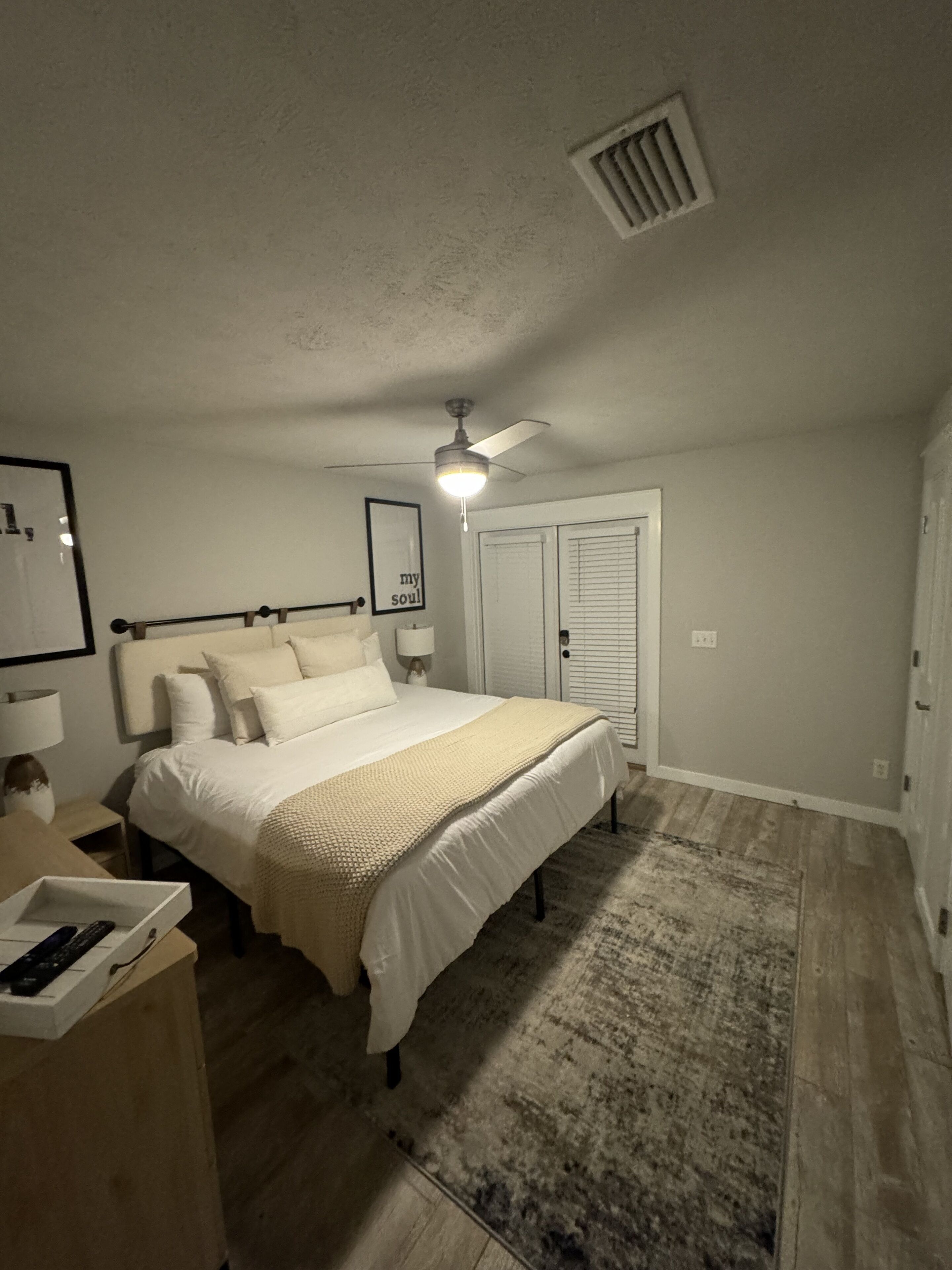 A bedroom with a bed, nightstand, and a ceiling fan.