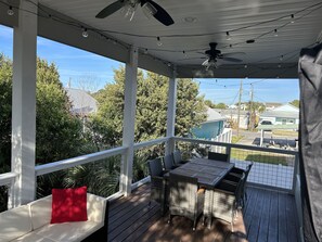 A covered porch with a table and chairs, a ceiling fan, and string lights. - 1 min. golf cart ride to the beach! Family-sized house w/ deck & fenced backyard (Panama City Beach)