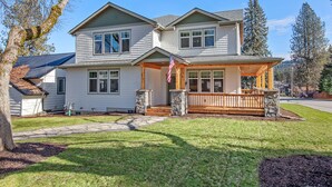 A two-story house with a front porch, stone steps, and a flag. - Tucked Away Paradise (Coeur d'Alene)