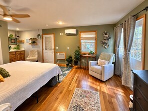 A bedroom with a bed, a chair, a desk, an air conditioning unit, and a window with curtains. - HOT TUB! Large deck, BBQ grill, fire pit & Arkansas Sunsets! (Eureka Springs)