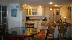A compact kitchen with white cabinets, a dining table with chairs, and a microwave.