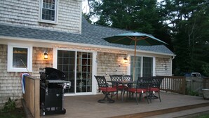 A covered patio with a grill, outdoor furniture, and string lights.