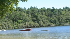 A lake with boats, a sandy beach, and a forested shoreline.