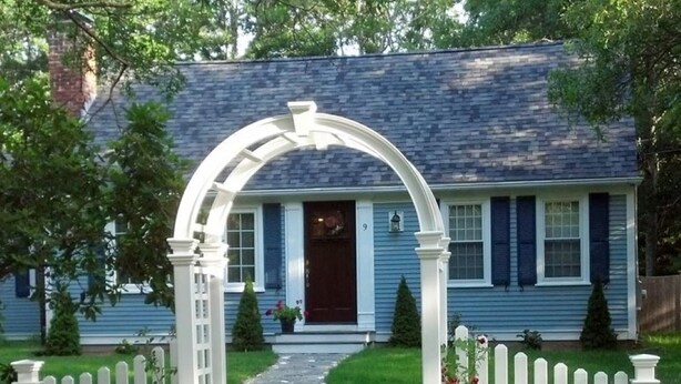 A house with a white picket fence, a stone pathway leading to the front door, and a blue exterior.