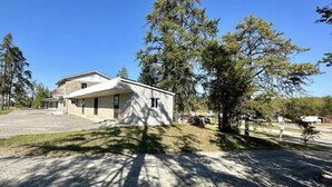 A single-story house with a sloped roof, a front porch, and a driveway leading to the entrance. - Pine Ridge Motel (Timmins)