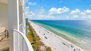 A balcony with a view of a beach, a pool, and a clear blue sky. - Ocean Ritz 1902 (Panama City Beach)