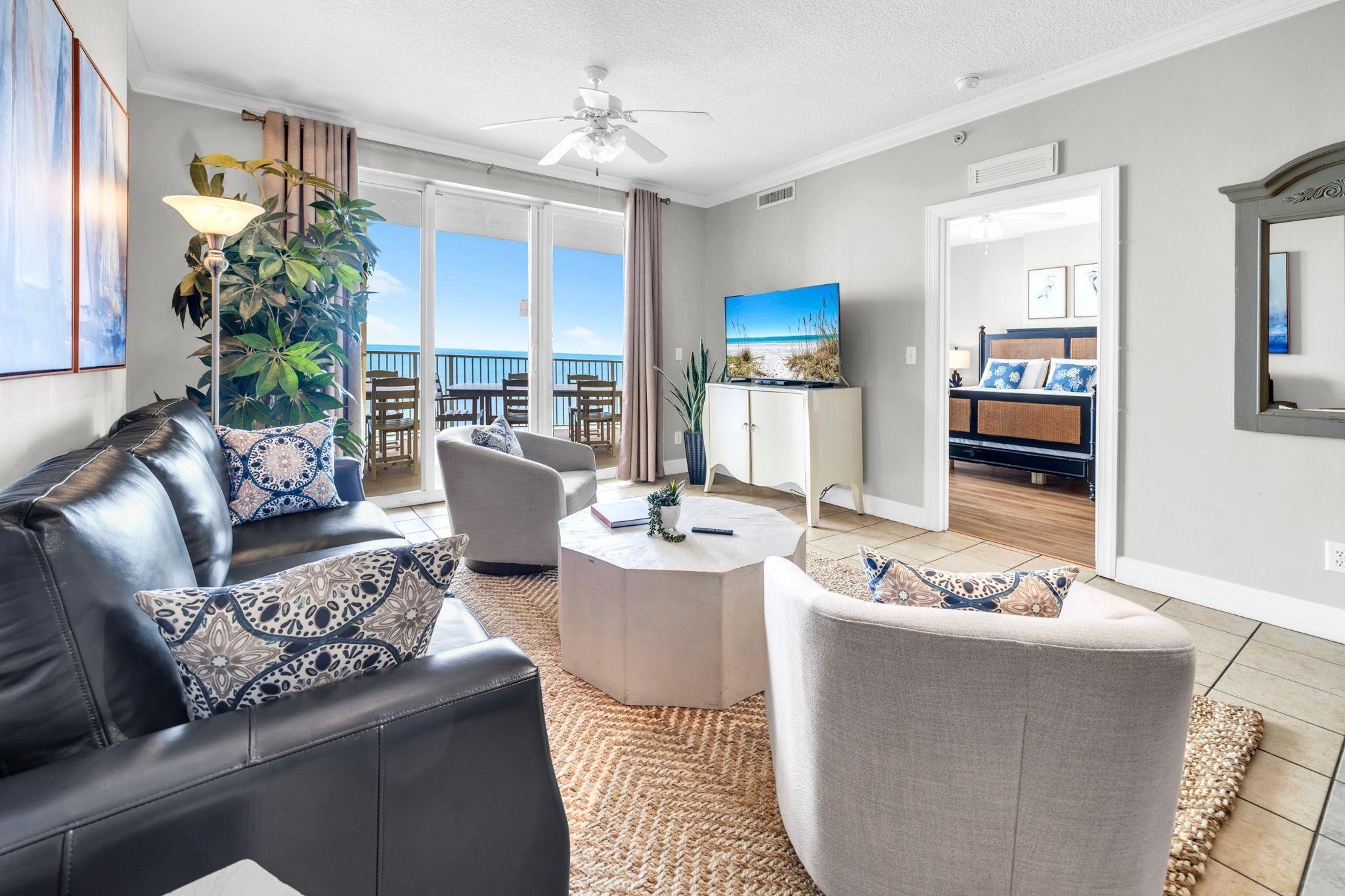 A modern living room with a leather sofa, a round coffee table, and a view of the balcony.