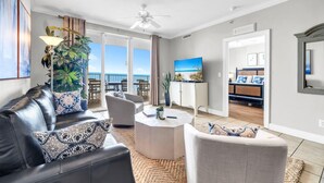 A modern living room with a leather sofa, a round coffee table, and a view of the balcony. - Tropic Winds 2308 (Panama City Beach)