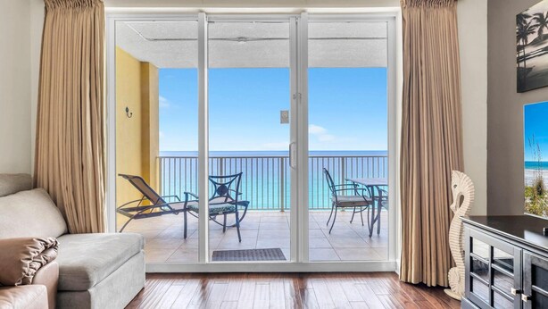 A room with a sliding glass door leading to a balcony with a view of the ocean. - Tropic Winds 1104 (Panama City Beach)
