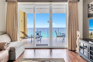 Una habitación con puerta de cristal corredera que da a un balcón con vista al océano.