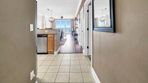 A hallway leading to a kitchen with a view of the outdoors. - Tropic Winds 1104 (Panama City Beach)
