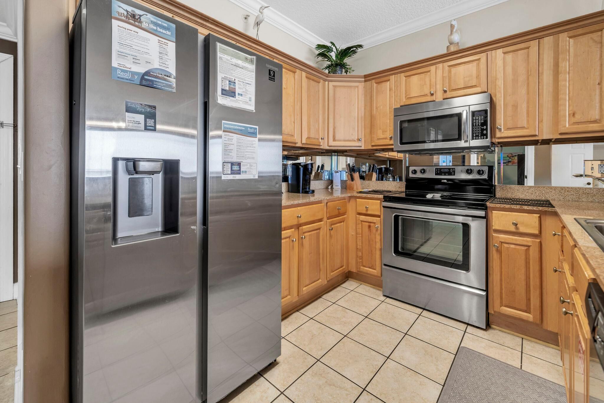 A kitchen with stainless steel appliances, wooden cabinets, and a tiled floor.