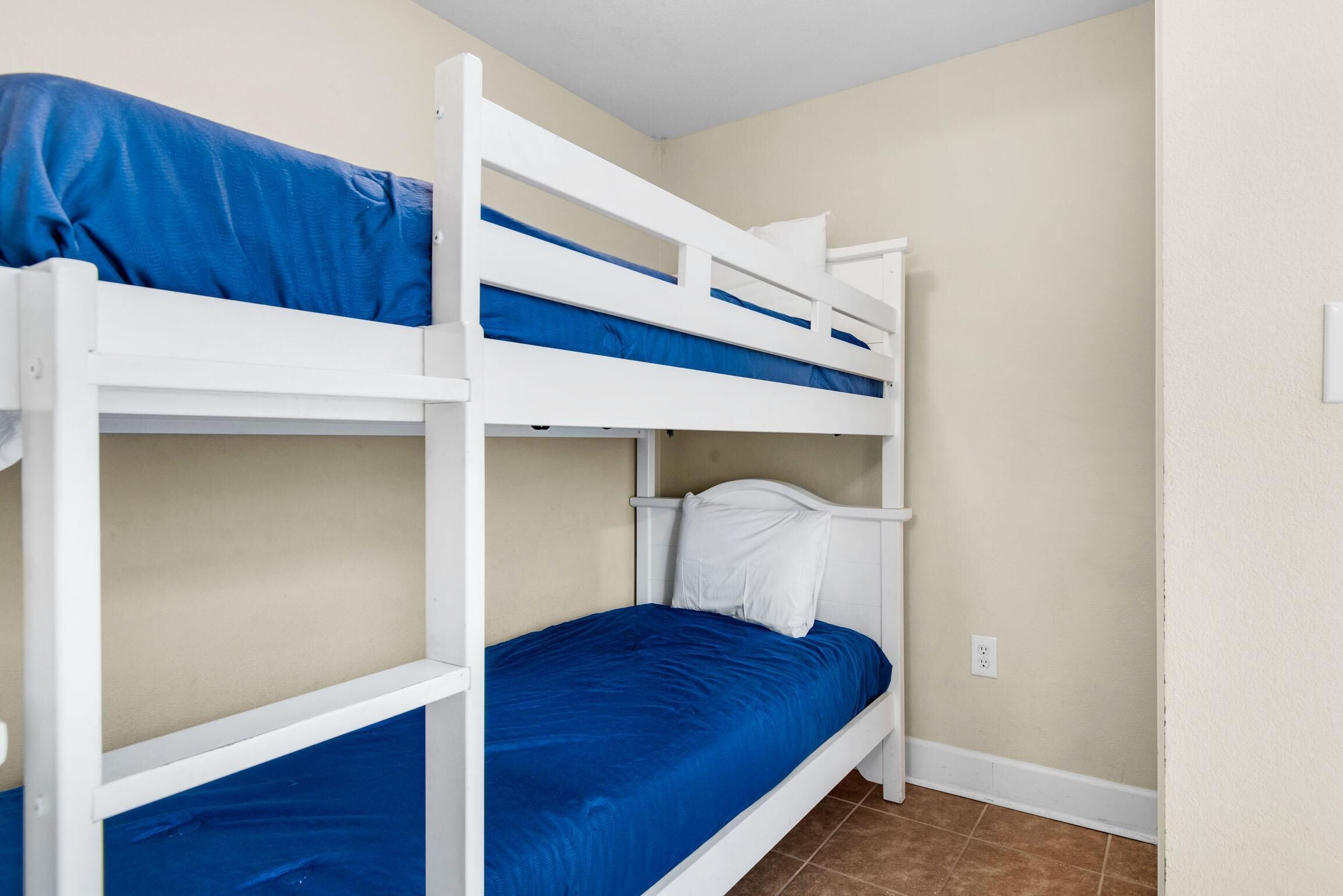 A bunk bed room with a blue mattress and white headboard.