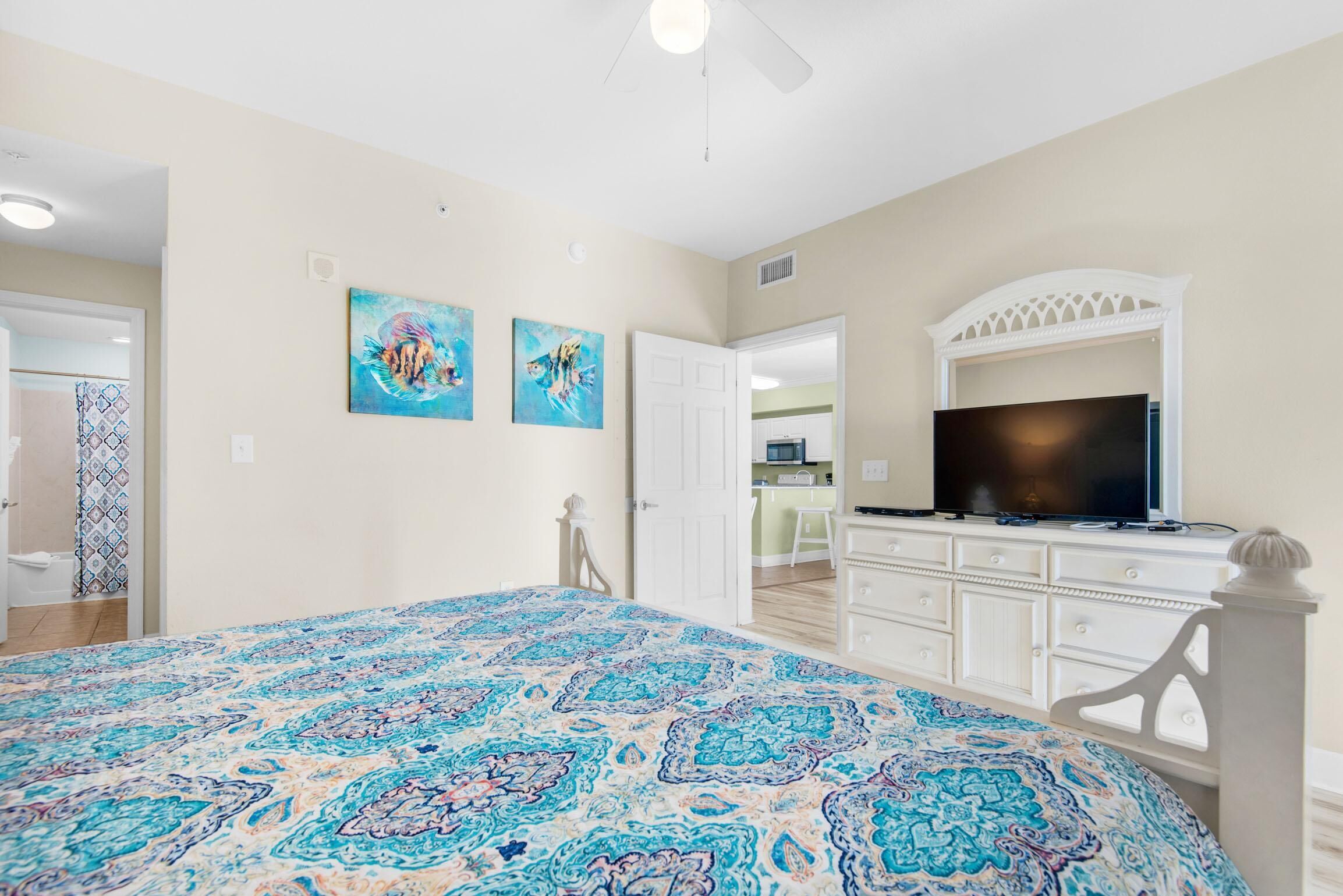 A bedroom with a bed, a TV, and artwork on the wall.